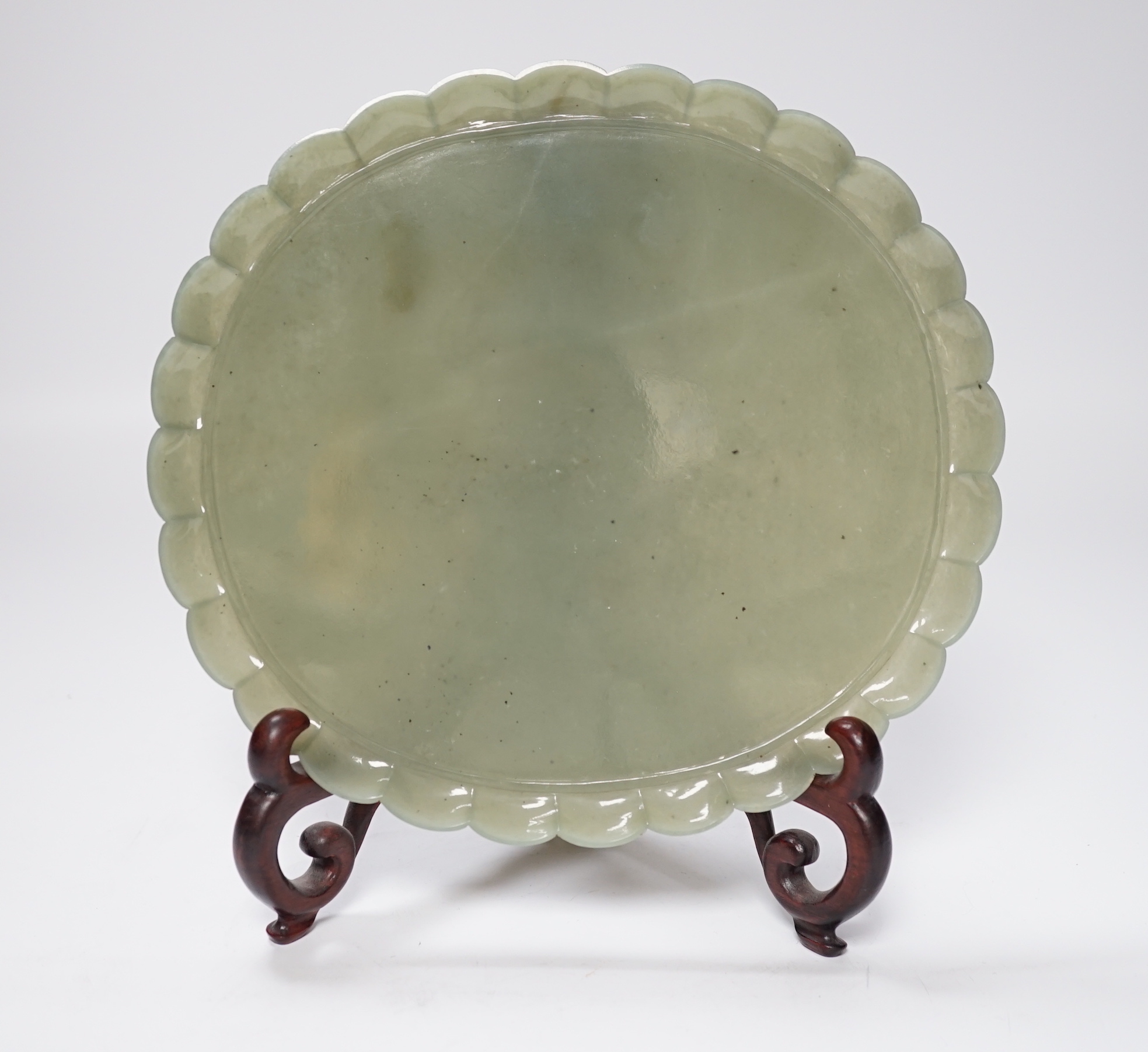 A Mughal style oval celadon jade dish, with petal lobed rim the underside carved with leaves, wood stand, 20cm